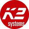 Logo K2 Systems sur fond rouge circulaire, affichant le texte blanc stylisé 'K2' et 'systems' pour les solutions solaires.